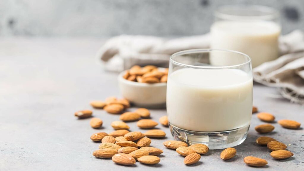 image representing a glass of almond milk along with some almonds