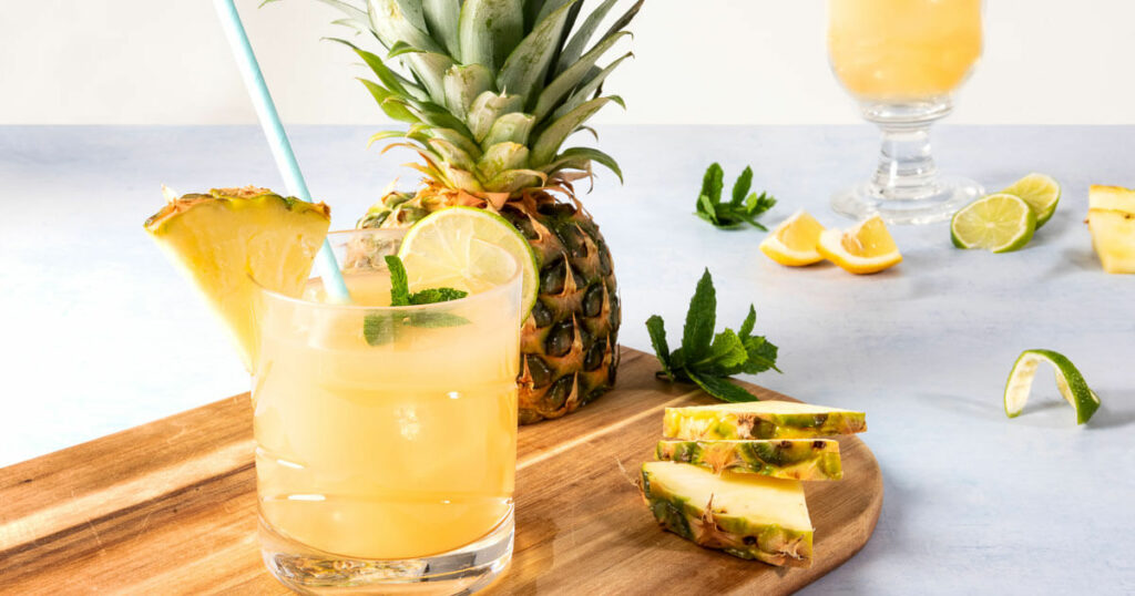 image representing pineapple juice alongside a pineapple slices